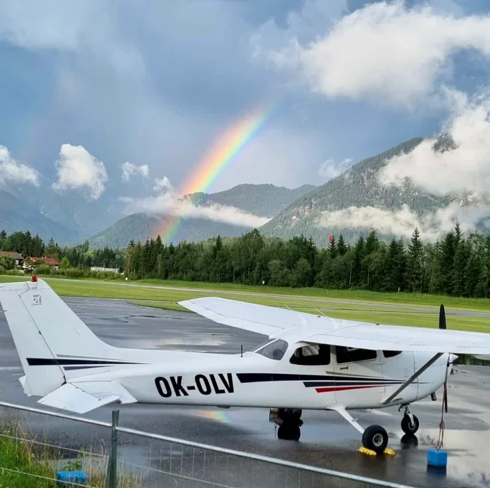 A Cessna 172 on a mountain ramp under a rainbow